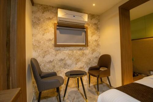 a hotel room with two chairs and a bed at Hotel Ratna Paradise Thane West in Thane