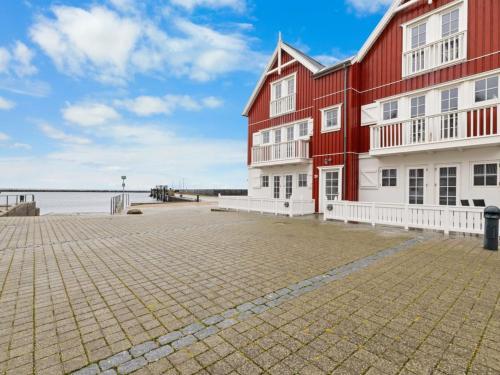 a red and white building next to a body of water at Apartment Terina - 5m from the sea by Interhome in Bagenkop