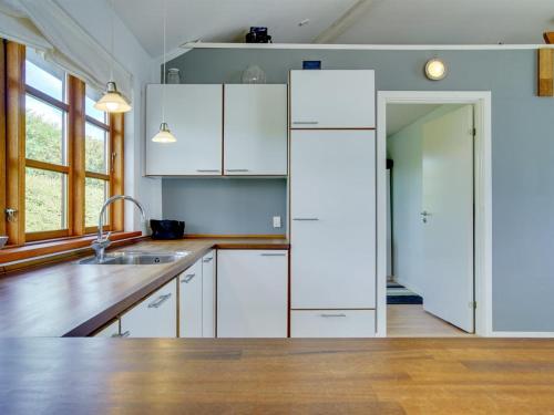 a kitchen with white cabinets and a sink at Holiday Home Botmar - 10m from the sea by Interhome in Ullerslev