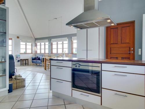 a kitchen with a stove top oven next to a living room at Holiday Home Botmar - 10m from the sea by Interhome in Ullerslev