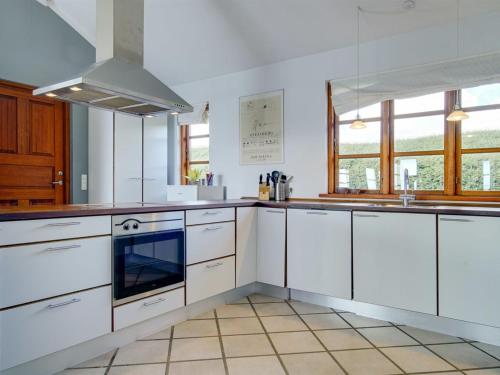 a kitchen with white cabinets and a stove top oven at Holiday Home Botmar - 10m from the sea by Interhome in Ullerslev