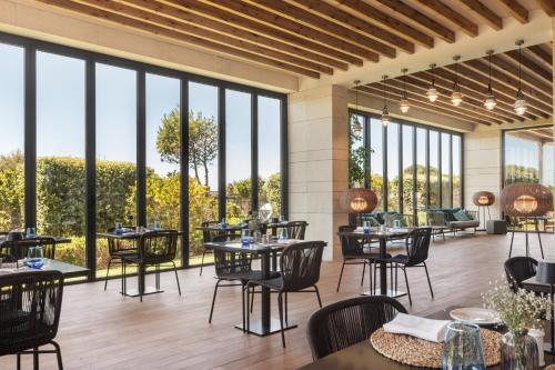 a restaurant with tables and chairs and large windows at Eurostars Cascais in Cascais