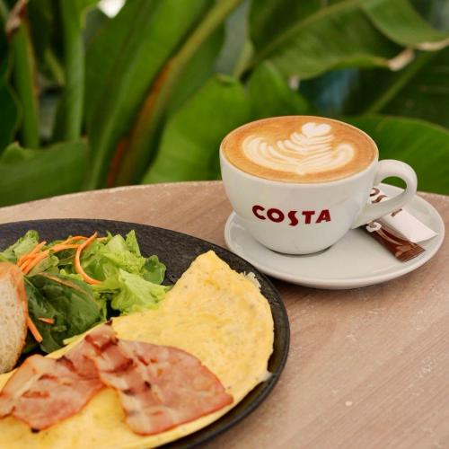 a cup of cappuccino and a plate of food and a salad at Piata Unirii Central Apartments in Iaşi