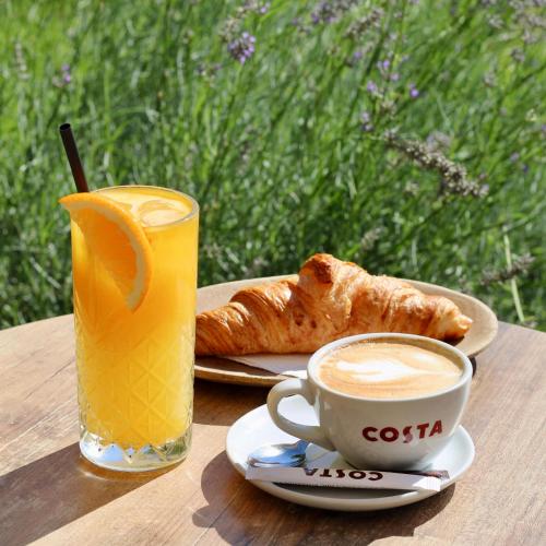 a table with a cup of coffee and a croissant and a drink at Piata Unirii Central Apartments in Iaşi