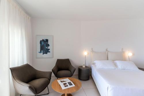 a bedroom with a bed and two chairs and a table at Lilium Hotel Santorini in Fira