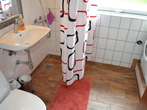 a bathroom with a toilet and a sink and a shower curtain at Holiday Home Claudia by Interhome in Bredebro