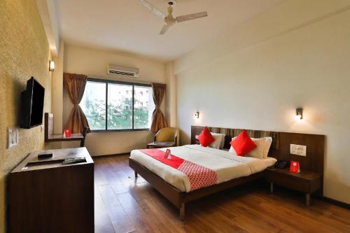 a bedroom with a bed with red pillows and a window at Hotel President Inn, Gandhinagar in Gandhinagar