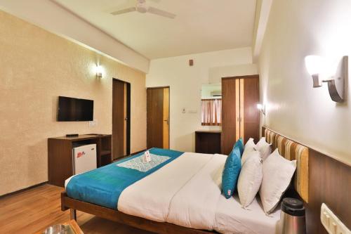 a hotel room with a bed with blue pillows at Hotel President Inn, Gandhinagar in Gandhinagar