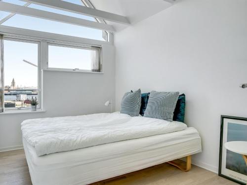 a white bedroom with a large bed and a window at Apartment Ninne - 50m from the sea by Interhome in Assens
