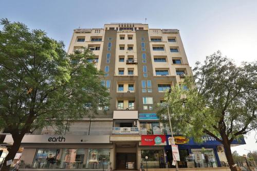 a tall building on a city street with trees at Hotel President Inn, Gandhinagar in Gandhinagar
