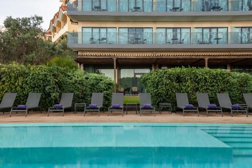 a row of lounge chairs next to a swimming pool at Eurostars Cascais in Cascais