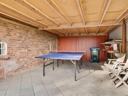 a ping pong table in a room with a brick wall at Holiday Home Hedda - 15km from the sea by Interhome in Ballum
