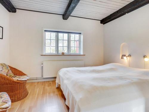 a white bedroom with a bed and a chair at Holiday Home Hedda - 15km from the sea by Interhome in Ballum