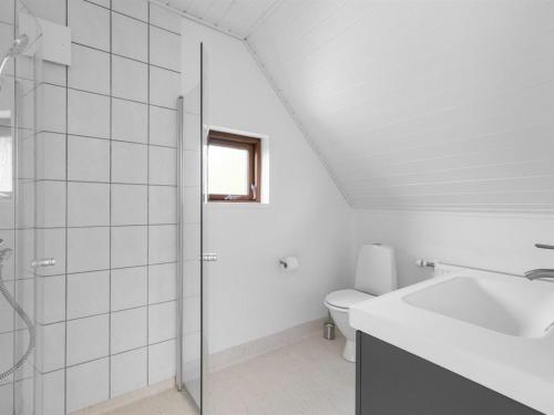 a white bathroom with a shower and a toilet at Holiday Home Jorith - 550m from the sea by Interhome in Tranekær