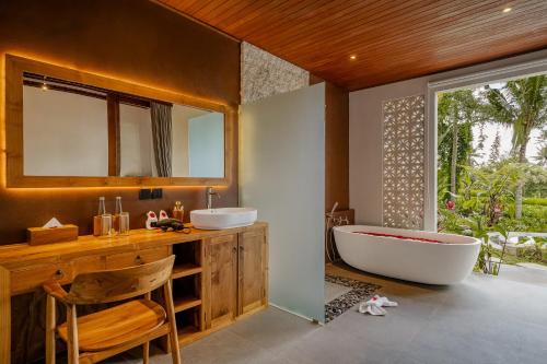 Un baño con dos lavabos y una bañera y una ventana. en View Merta Ubud Villa, en Ubud