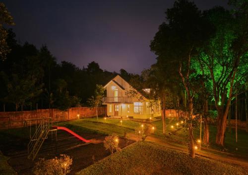 a house with lights in the yard at night at Kedara Resort Wayanad by VOYE HOMES in Sultan Bathery