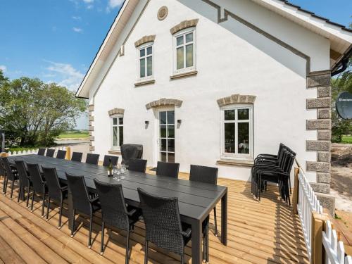 a wooden deck with a black table and chairs at Holiday Home Guthorm by Interhome in Højer