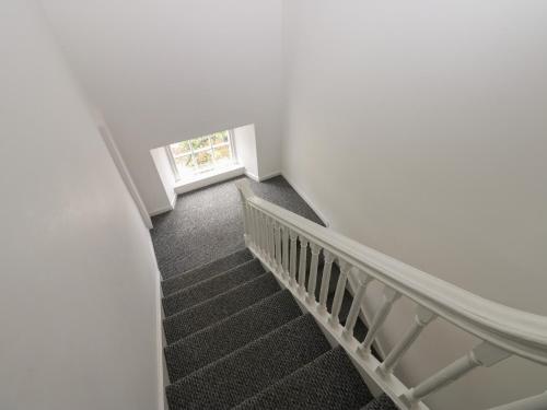 a winding staircase with a window in a white room at Georgian Town House in Whitehaven