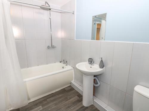 a white bathroom with a sink and a bath tub at Georgian Town House in Whitehaven