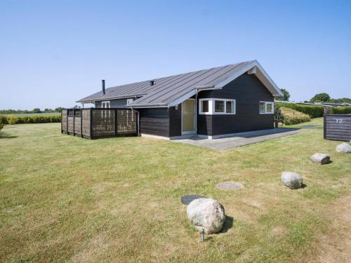 a black house in a field with a large yard at Holiday Home Iorund - 550m from the sea by Interhome in Haderslev