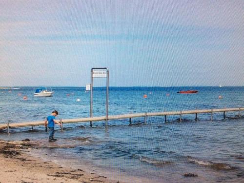 a young boy standing on the beach near the water at Holiday Home Iorund - 550m from the sea by Interhome in Haderslev