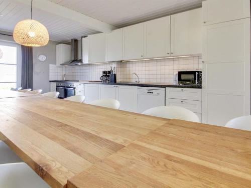 una gran cocina con una larga mesa de madera y sillas blancas. en Holiday Home Annagrete - 12km from the sea by Interhome, en Højer