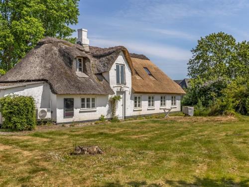 a thatched cottage with a grass roof on a yard at Holiday Home Aughe - 25km from the sea by Interhome in Bredebro