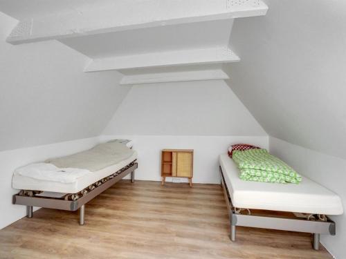two beds in a room with white walls and wooden floors at Holiday Home Aughe - 25km from the sea by Interhome in Bredebro