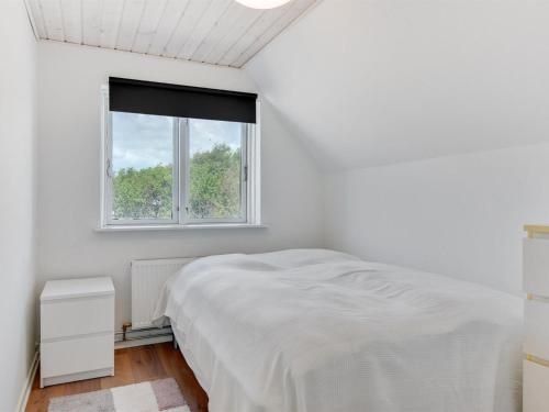 a white bedroom with a bed and a window at Holiday Home Iina - 13km from the sea by Interhome in Bredebro