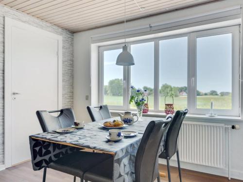 a dining room with a table and chairs and windows at Holiday Home Iina - 13km from the sea by Interhome in Bredebro