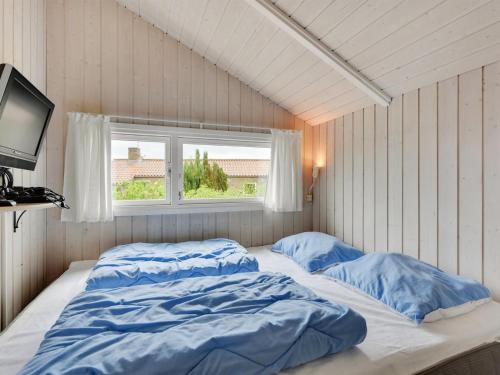 a bed with blue sheets in a room with a window at Holiday Home Hwiting - 200m from the sea by Interhome in Broager
