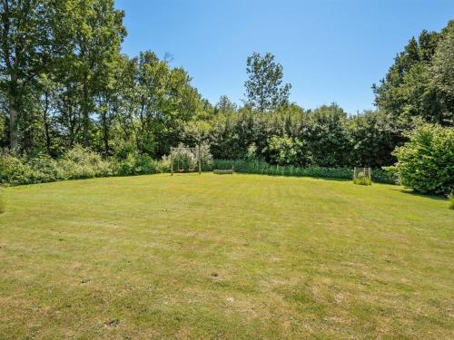 a large grass field with trees in the background at Holiday Home Hasti - 700m from the sea by Interhome in Tranekær