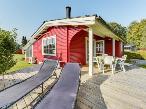 a red house with a deck with a table and chairs at Holiday Home Florencia - 200m from the sea by Interhome in Binderup Strand