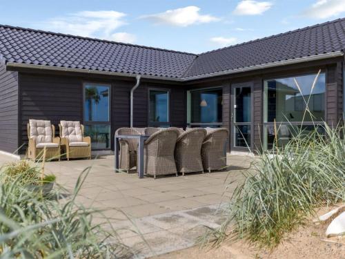 a patio with chairs and a table and windows at Holiday Home Eino - 30m from the sea by Interhome in Sjølund