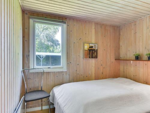 a bedroom with a bed and a window and a chair at Holiday Home Leandra - 600m from the sea by Interhome in Augustenborg