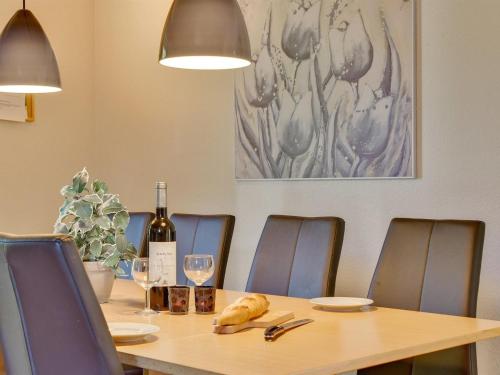 a wooden table with chairs and a bottle of wine at Holiday Home Fausta - 150m to the fjord by Interhome in Gråsten
