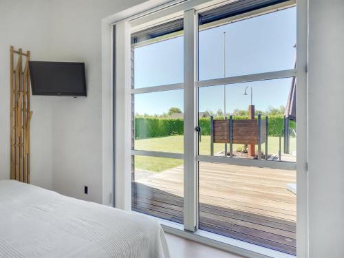 a bedroom with a large window with a view of a deck at Holiday Home Hans - 700m from the sea by Interhome in Neder Lysabild
