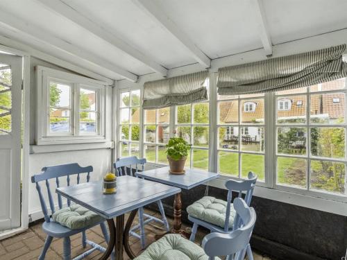 a dining room with a table and chairs and windows at Holiday Home Ajna - 9-8km from the sea by Interhome in Tønder