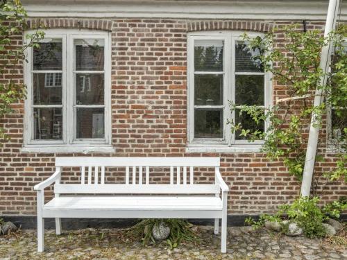 a white bench sitting in front of a brick building at Holiday Home Ajna - 9-8km from the sea by Interhome in Tønder