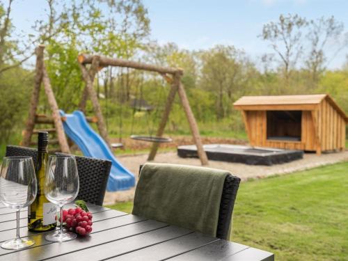 a wooden table with wine glasses and a playground at Holiday Home Eylar - 28km from the sea by Interhome in Toftlund