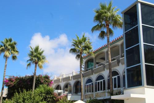 a building with palm trees in front of it at Rethymno Mare & Water Park in Rethymno Town