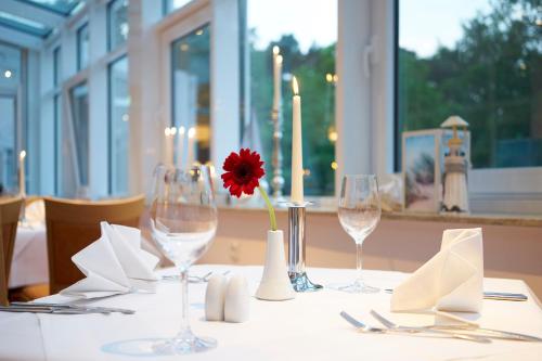 a table with wine glasses and a red flower on it at Dorint Seehotel Binz-Therme in Binz