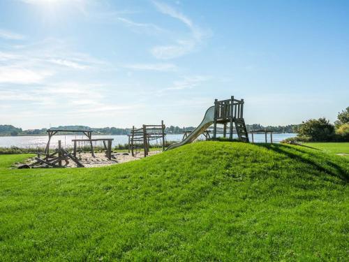 a playground on a grassy hill next to the water at Holiday Home Skjalm - 100m to the inlet by Interhome in Gråsten