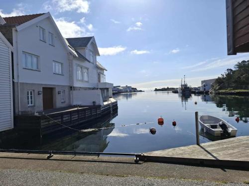 a river with a house and a boat in the water at Ocean Front Garden in Skudeneshavn