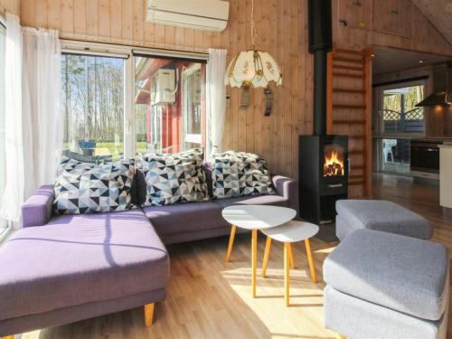 a living room with a purple couch and a fireplace at Holiday Home Edy - 25km from the sea by Interhome in Toftlund