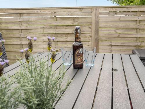 a bottle of beer sitting on a wooden table with glasses at Holiday Home Inda - 10km from the sea by Interhome in Højer