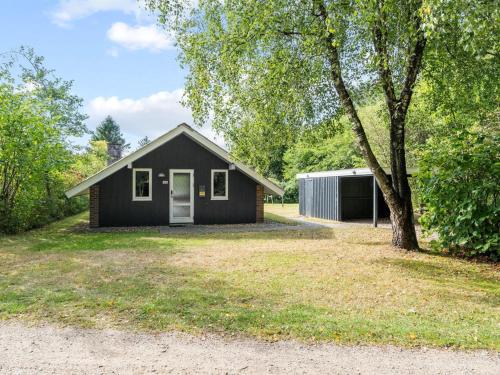 a small black house with a tree in the yard at Holiday Home Pance - 20km to the fjord by Interhome in Toftlund
