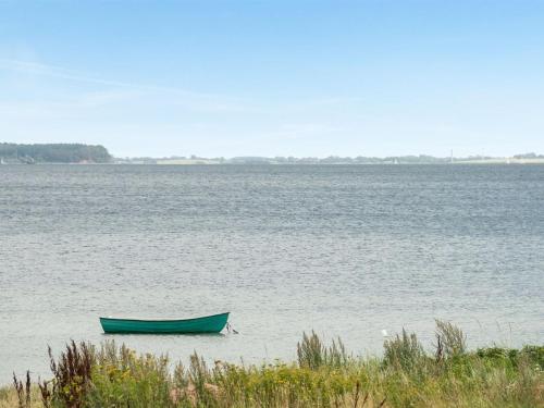 a green boat sitting in the middle of a large body of water at Holiday Home Elain - from the sea by Interhome in Broager