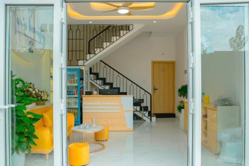 a lobby with a staircase and yellow chairs and tables at Tom's Homestay 2 in Hue