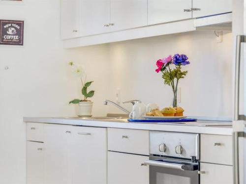 a kitchen with white cabinets and a vase of flowers at Apartment Joar - 5m to the inlet by Interhome in Gråsten